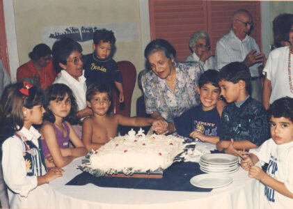 OLGA e as crianças rodeando o bolo do seu 85º aniversário.